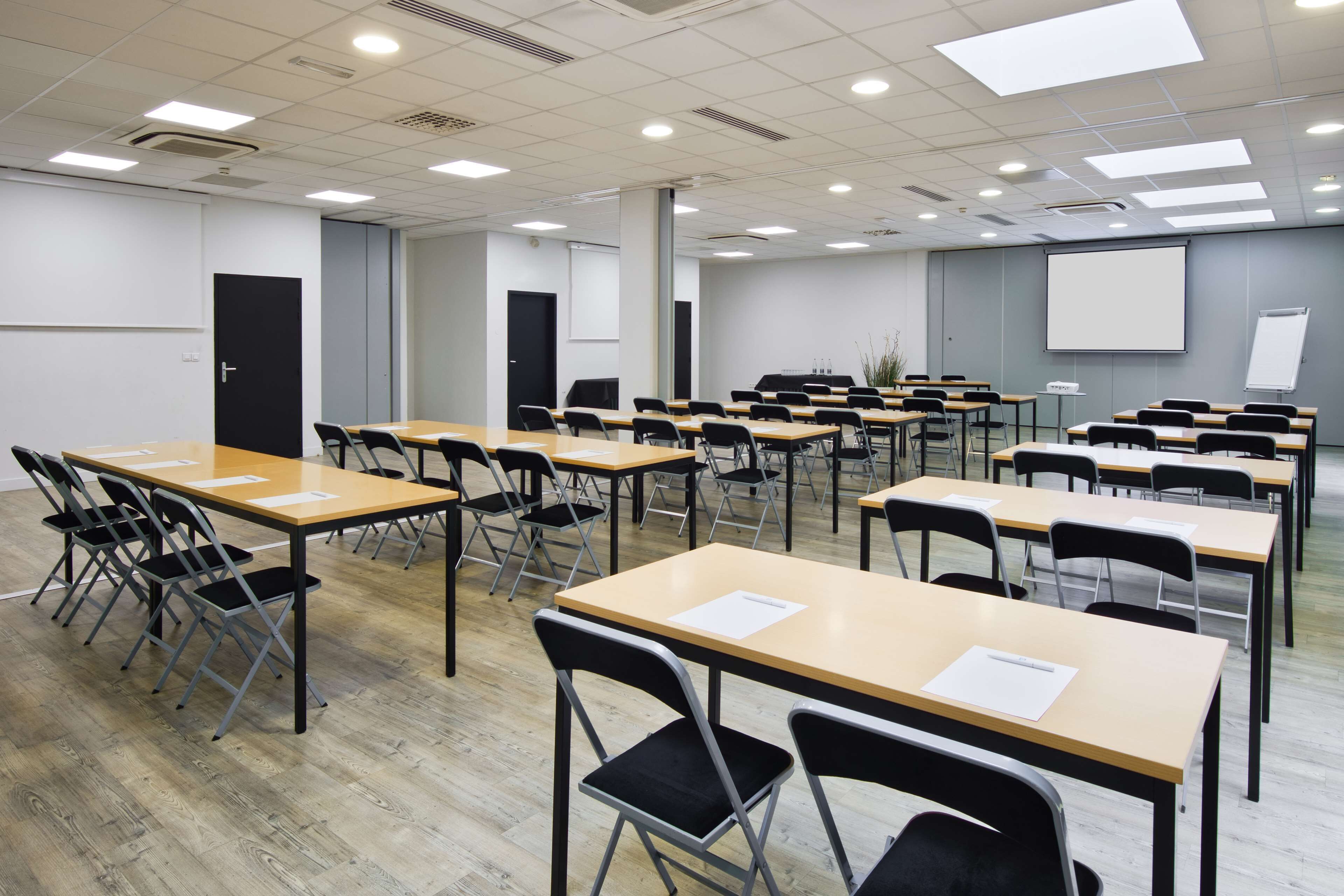 A classroom with rows of desks and chairs, a projector screen, and a whiteboard.