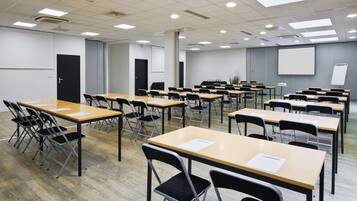 A classroom with rows of desks and chairs, a projector screen, and a whiteboard.