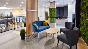 A modern indoor space with a blue sofa, a round table, and two armchairs. - Sure Hotel by Best Western Nantes Beaujoire (Nantes)