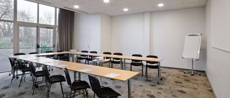 A conference room with a long table, chairs, a whiteboard, and large windows.