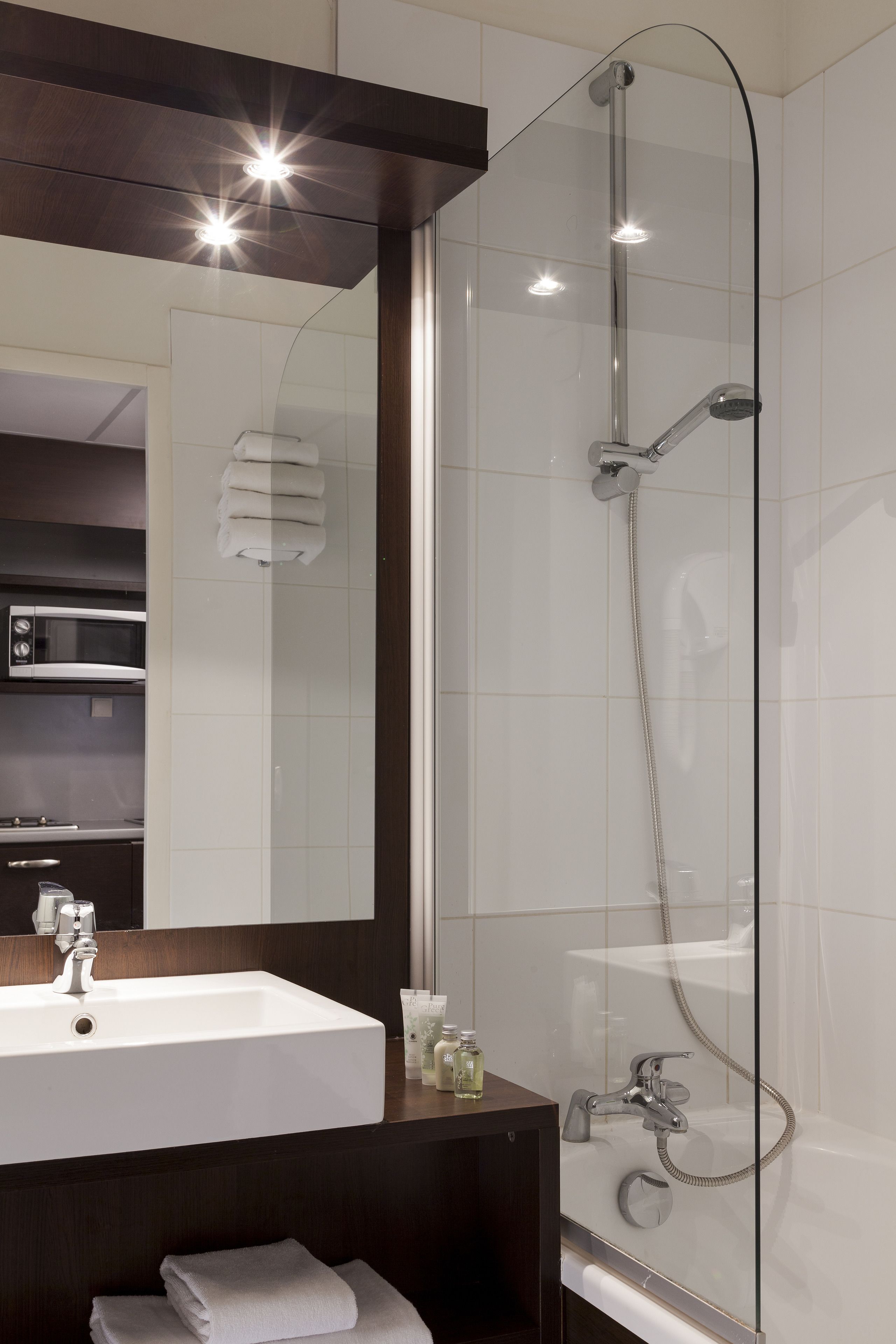 A modern bathroom with a glass-enclosed shower, a white sink, and a dark wooden vanity.