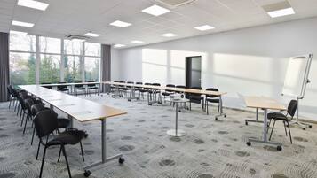 A conference room with a long table, chairs, a whiteboard, and large windows.