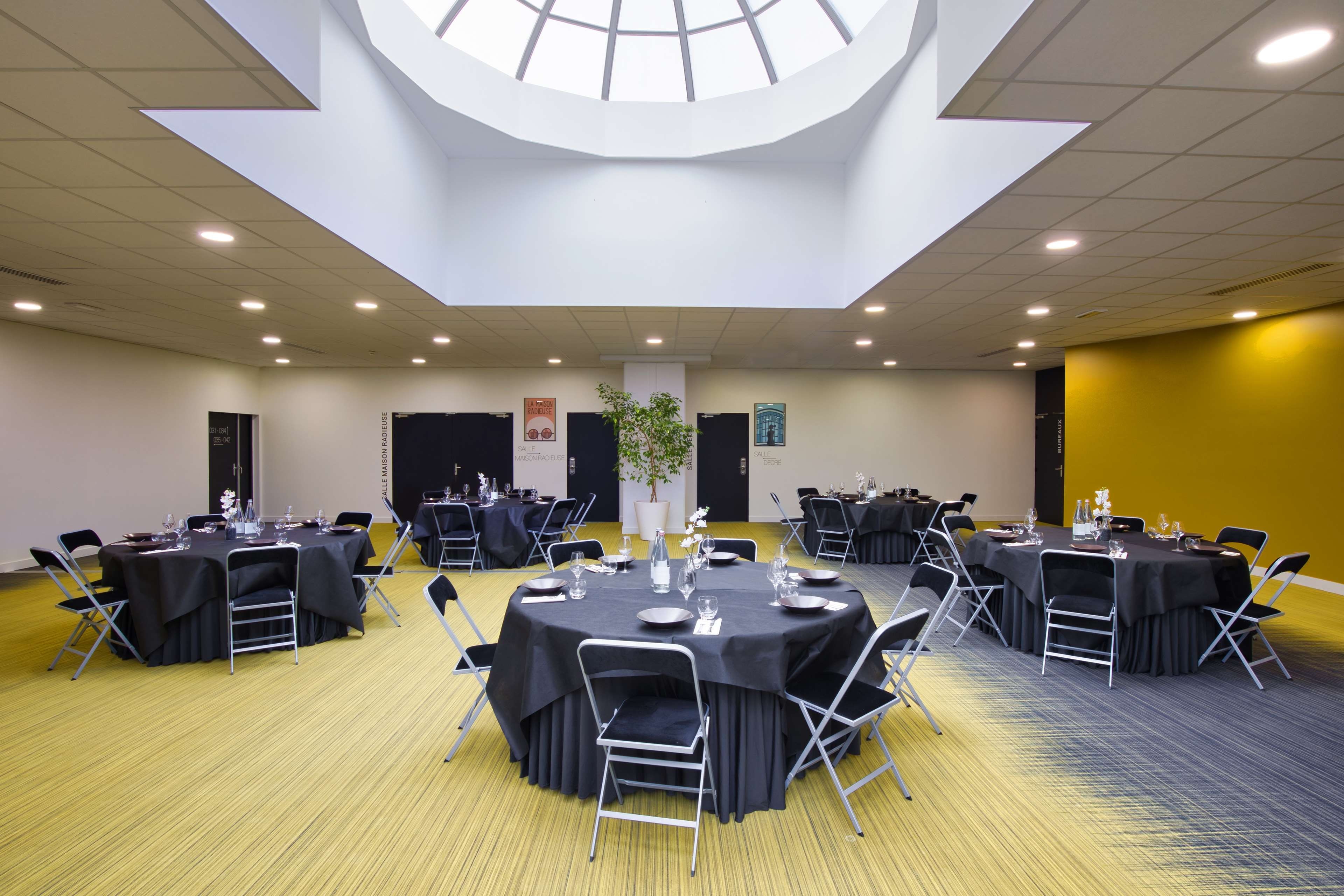 A conference room with round tables, chairs, and a central plant.