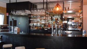 A bar area with stools, shelves of bottles, glasses, and a coffee machine. - Sure Hotel by Best Western Nantes Beaujoire (Nantes)