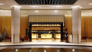 Un hall d’hôtel moderne comprenant un comptoir d’accueil, un élément décoratif aquatique et un espace salon.