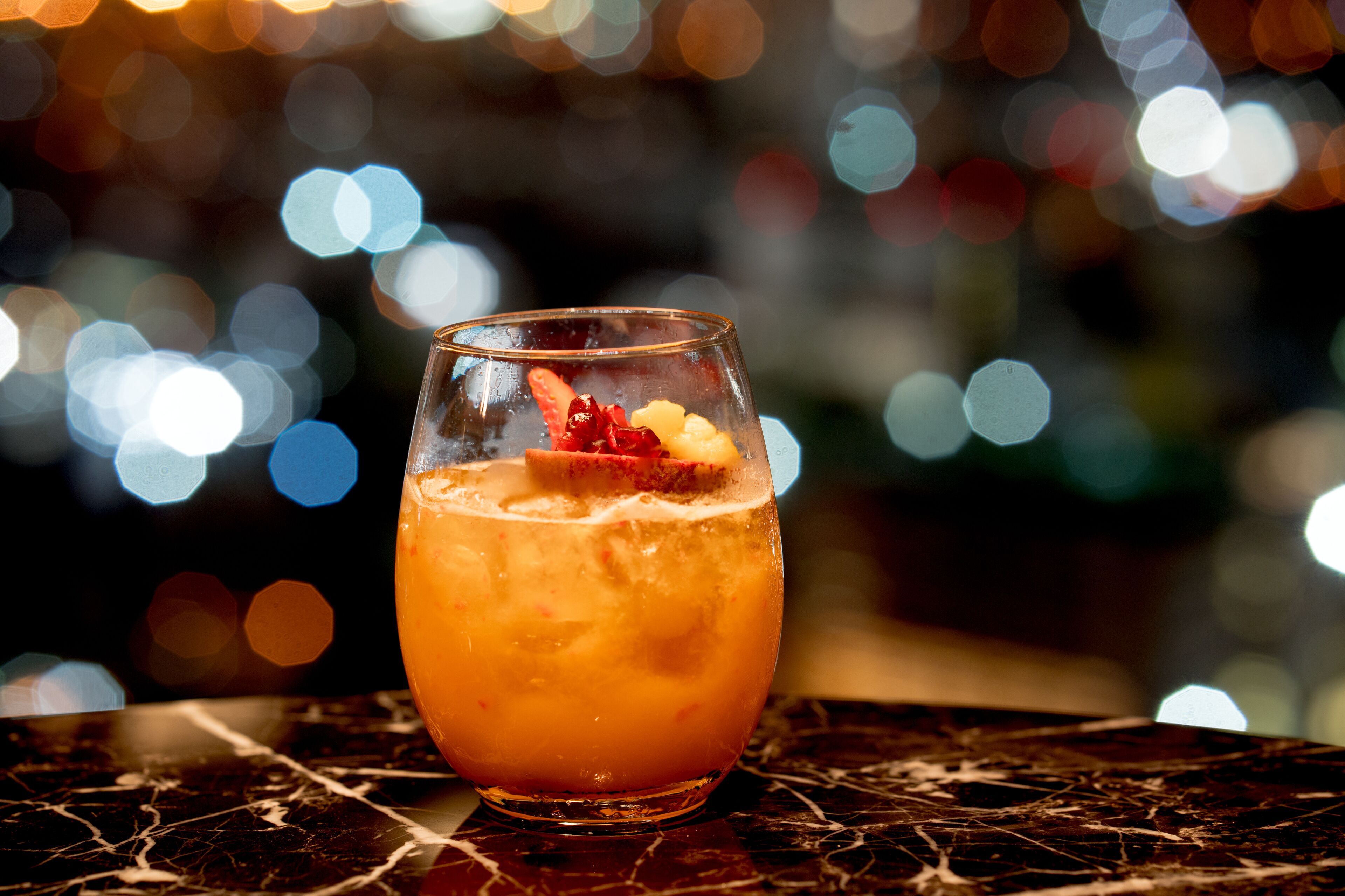 Un verre de boisson à l’orange, agrémenté d’une garniture, posé sur une surface en marbre.