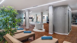 A modern spa area with wooden flooring, lounge chairs, and a large water feature. - Occidental Roca Negra – Adults Only (Agaete)