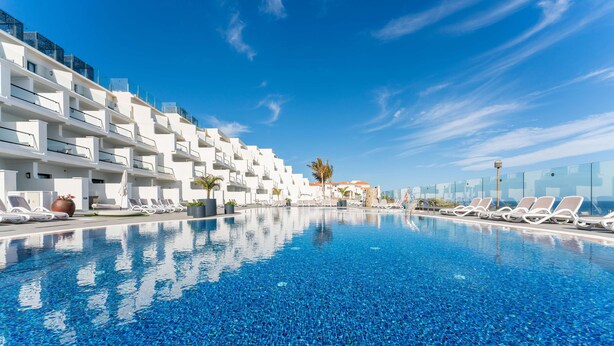 A modern hotel with a large swimming pool, white balconies, and lounge chairs. - Occidental Roca Negra – Adults Only (Agaete)