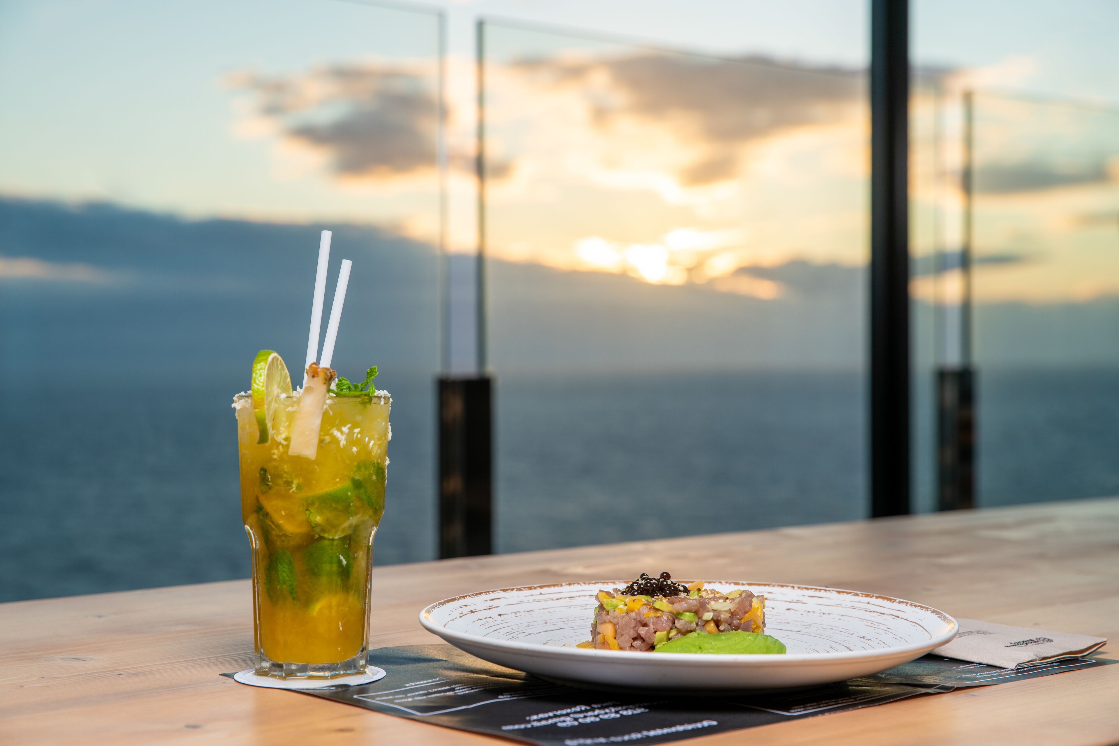 Une table avec un verre de boisson fraîche et une assiette de nourriture, offrant une vue panoramique.