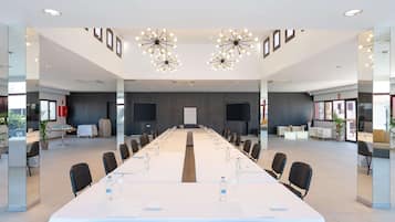 A modern conference room with a long table, chairs, and a projector screen.