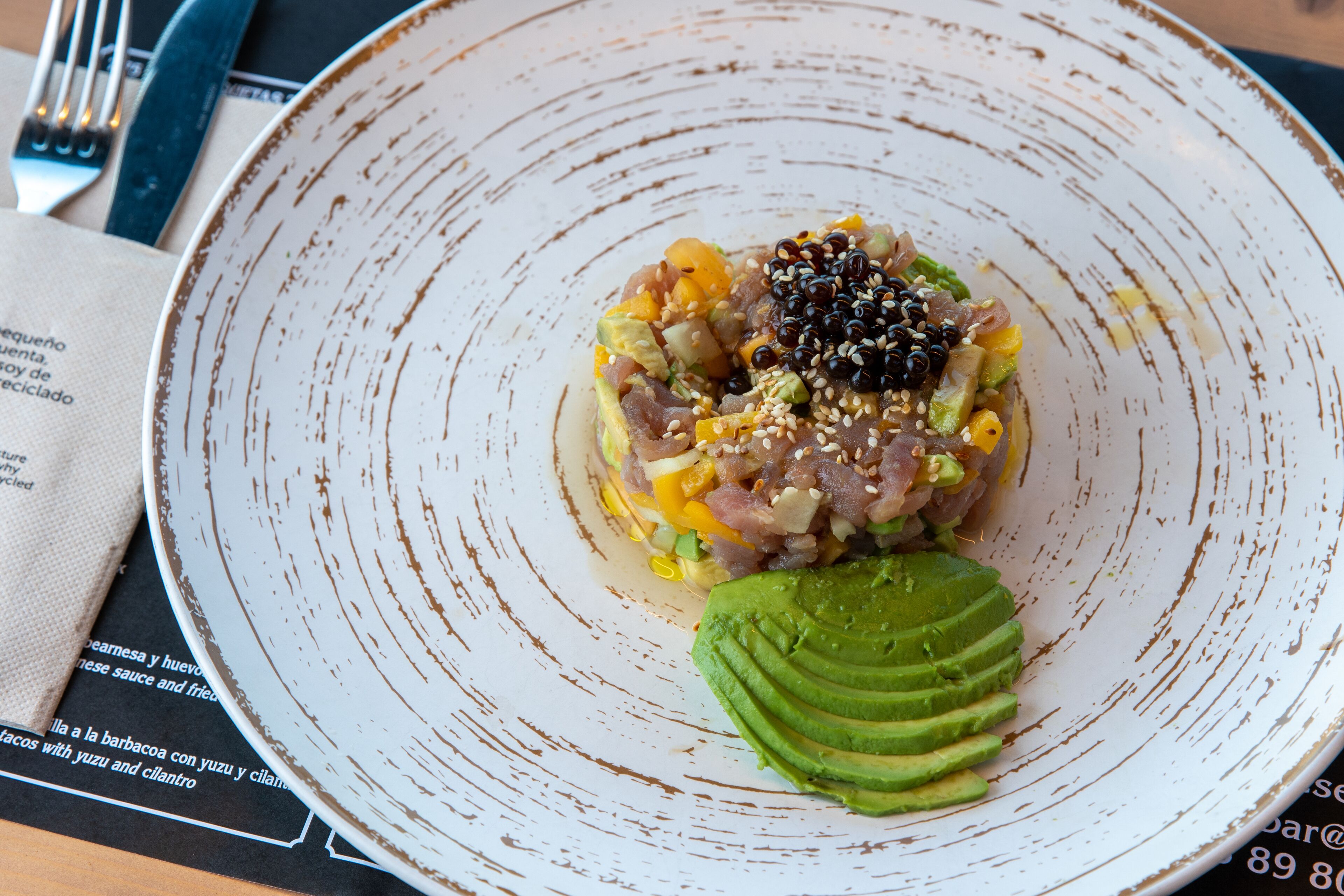 A plate of food with avocado and a variety of toppings.