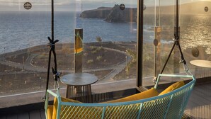 A hanging chair with a yellow cushion overlooking a coastal view. - Occidental Roca Negra – Adults Only (Agaete)
