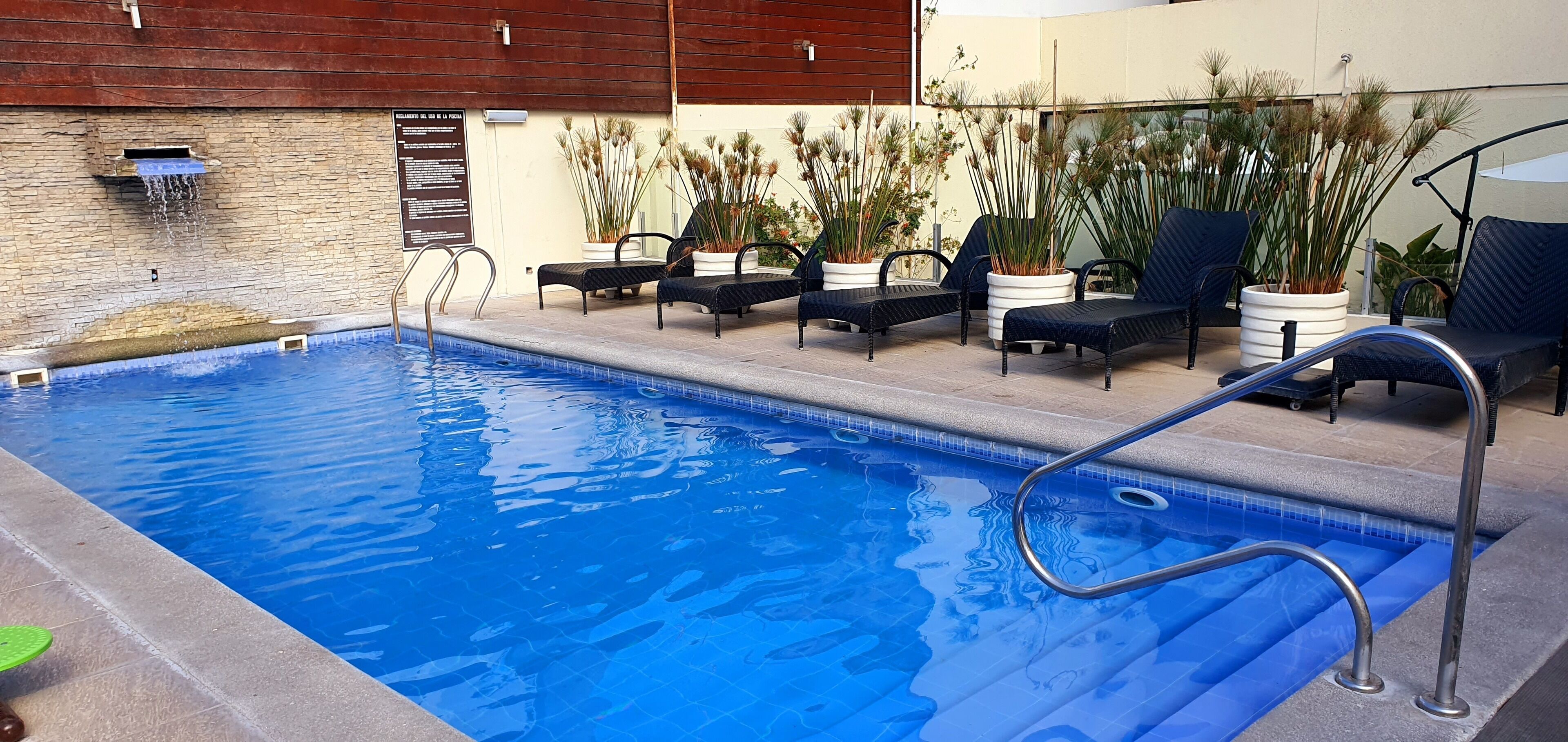 Una piscina con sillas de descanso y plantas en macetas.