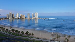 Un paisaje urbano costero con edificios altos, una playa y un cielo azul despejado.