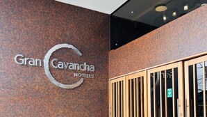 Entrada de hotel con un cartel que dice "Gran Cavancha Hotels" y una puerta de madera con un panel de vidrio.