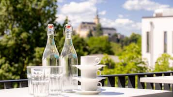 A balcony with a table set for tea, featuring two bottles and several cups.