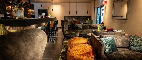 A modern lounge area with sofas, a round ottoman, and a bar counter.