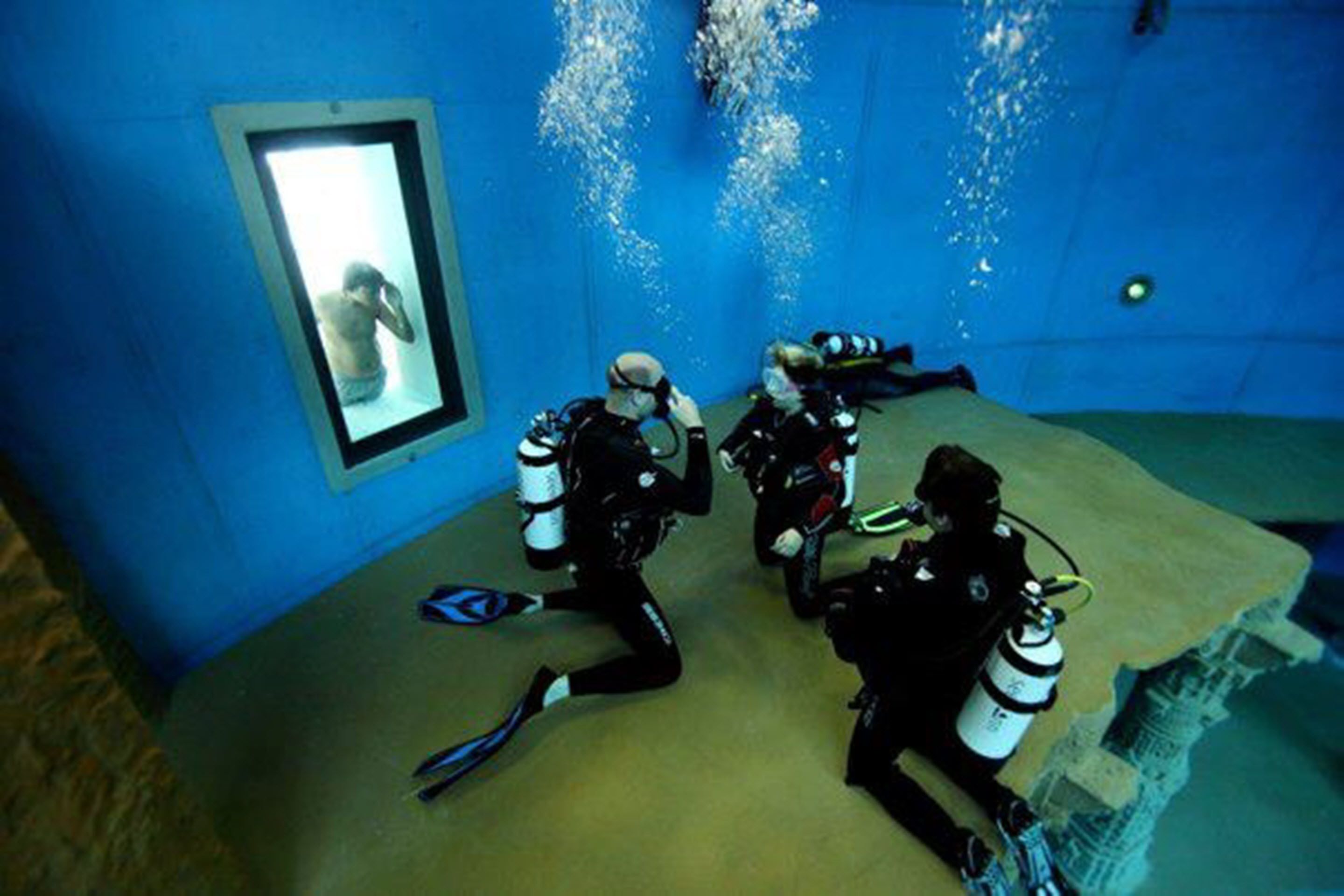 A room with blue walls, a window, and a large mirror.