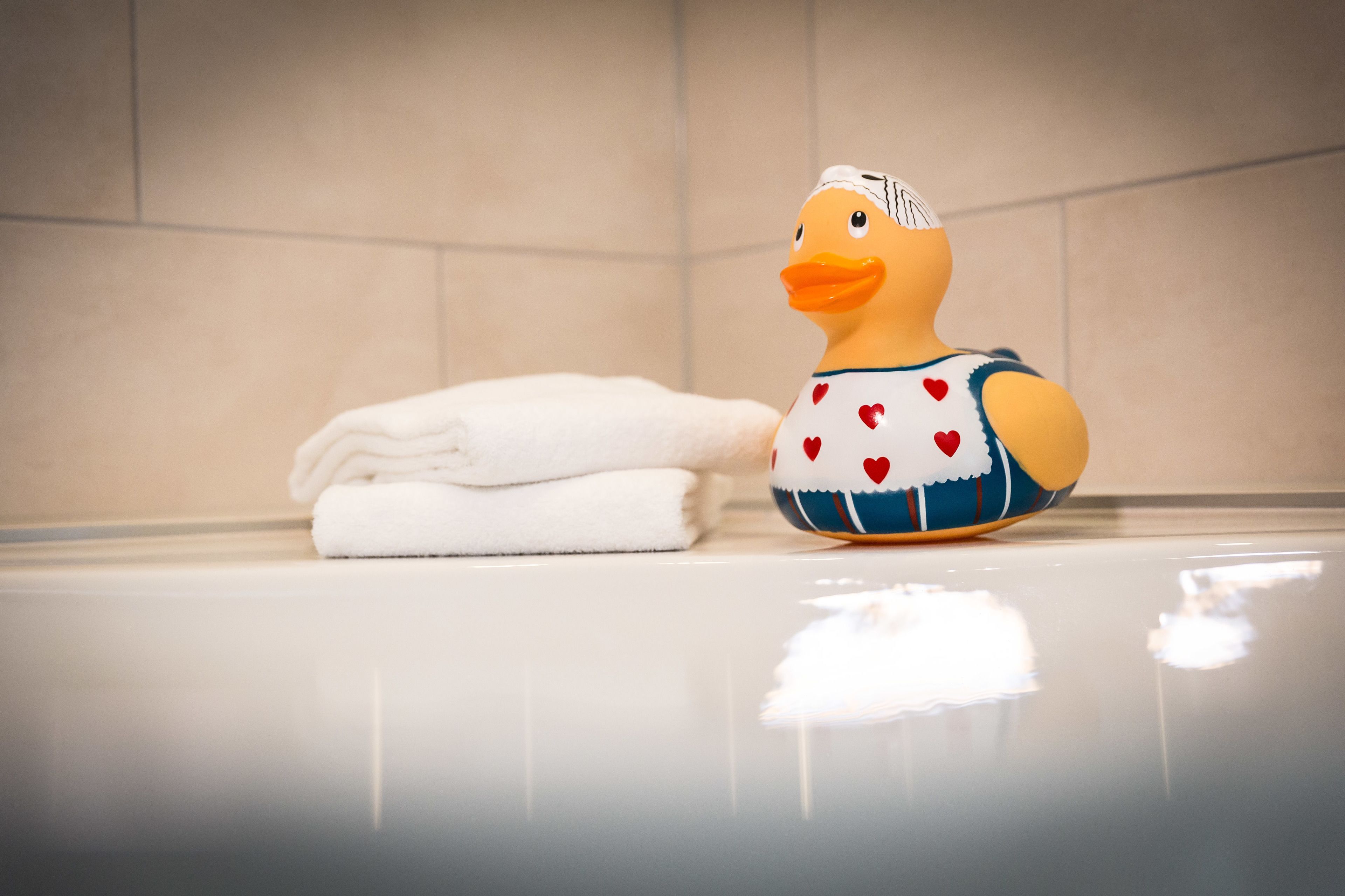 A duck-shaped bath mat with a towel stacked beside it.