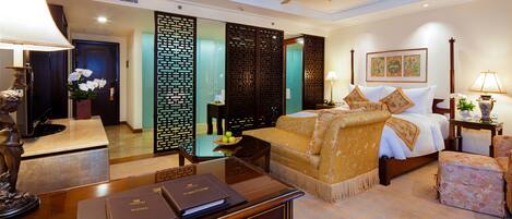 A hotel room with a bed, bedside table, lamp, decorative items, and a desk with a folder.