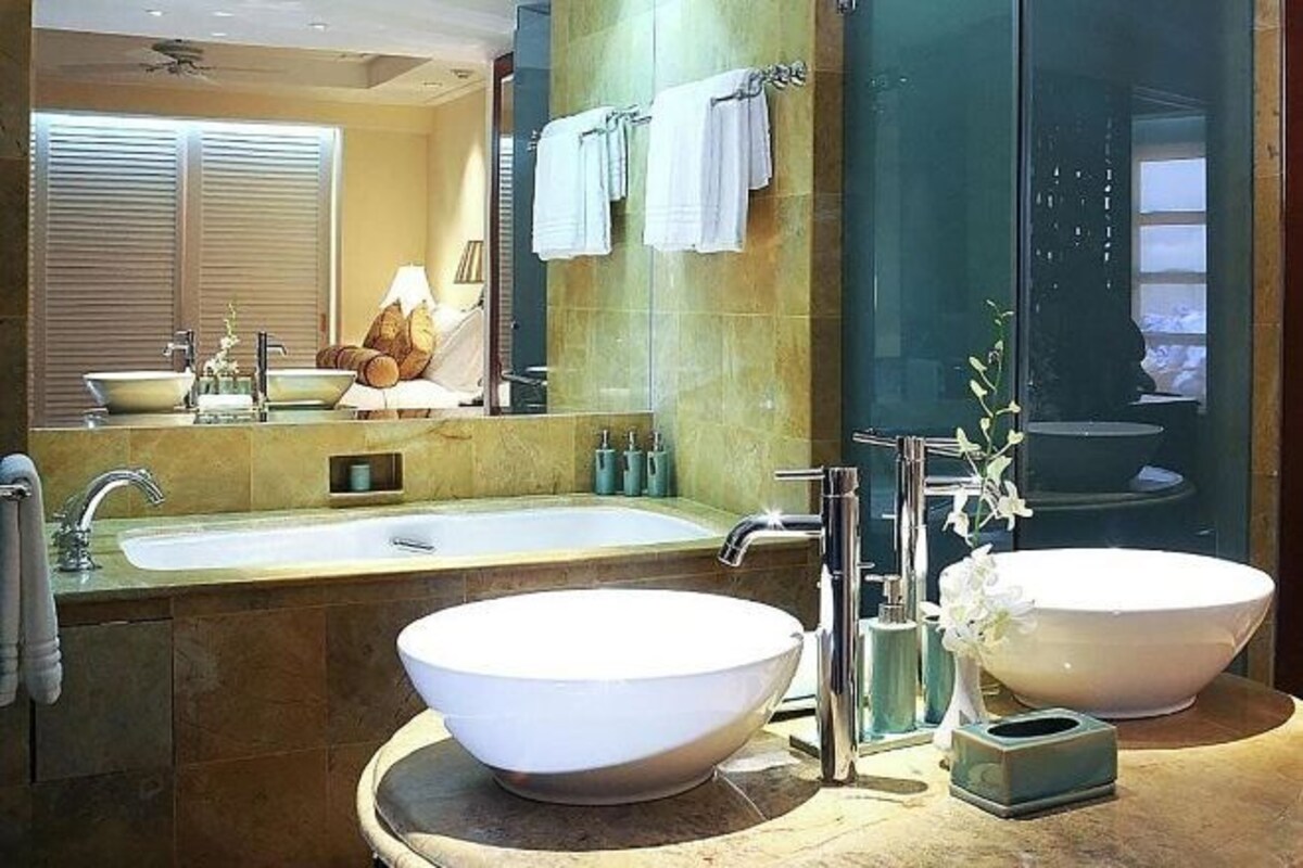 A modern bathroom with two large white vessel sinks, a glass-enclosed shower, and a mirror reflecting the room.