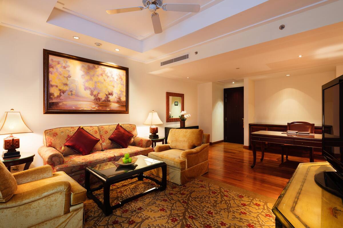 A spacious living room with a ceiling fan, a large painting, and a dining area with a table and chairs.