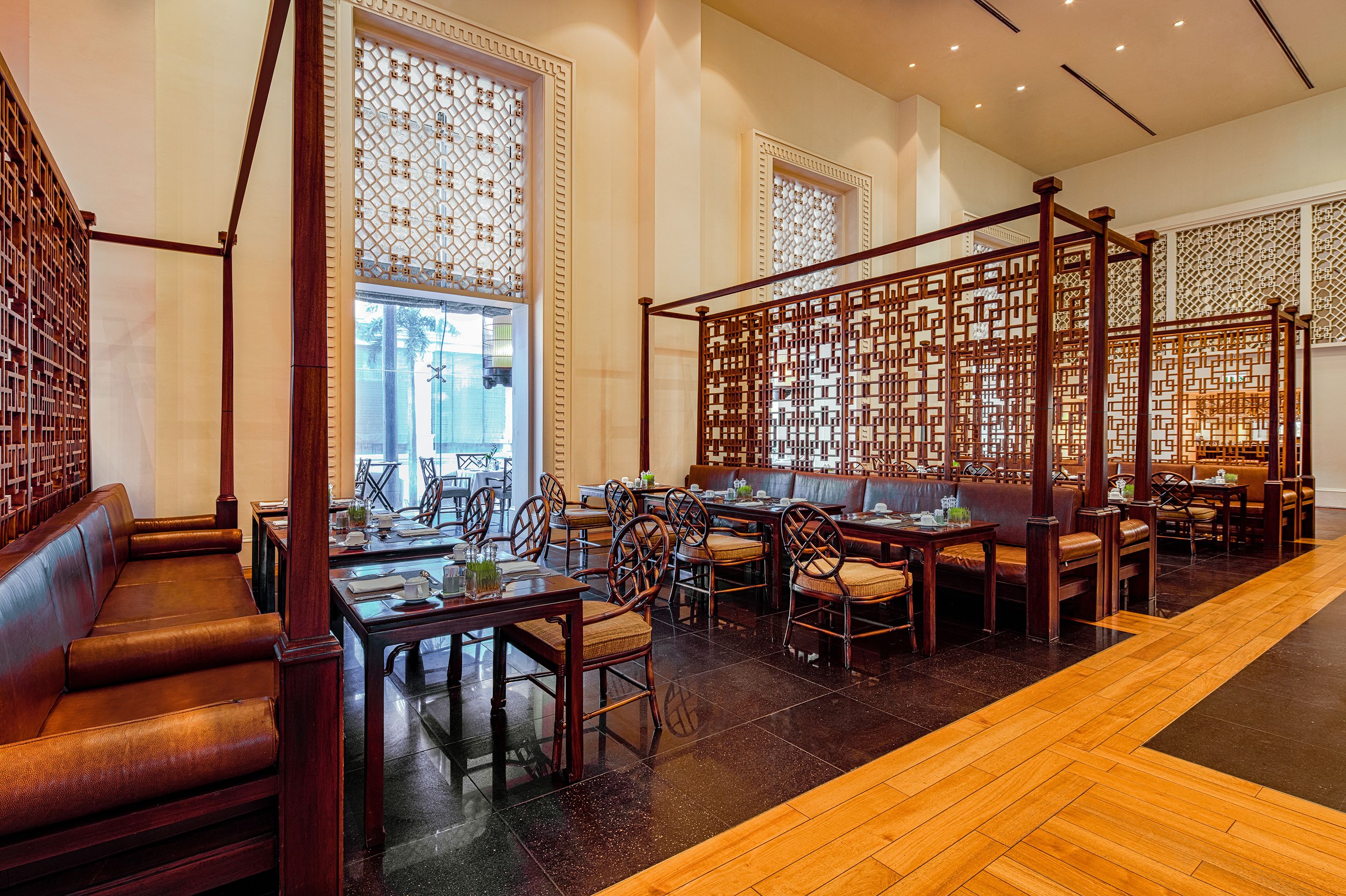 A traditional-style restaurant with wooden furniture, a central seating area, and decorative screens.