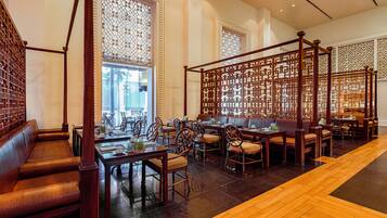 A traditional-style restaurant with wooden furniture, a central seating area, and decorative screens.