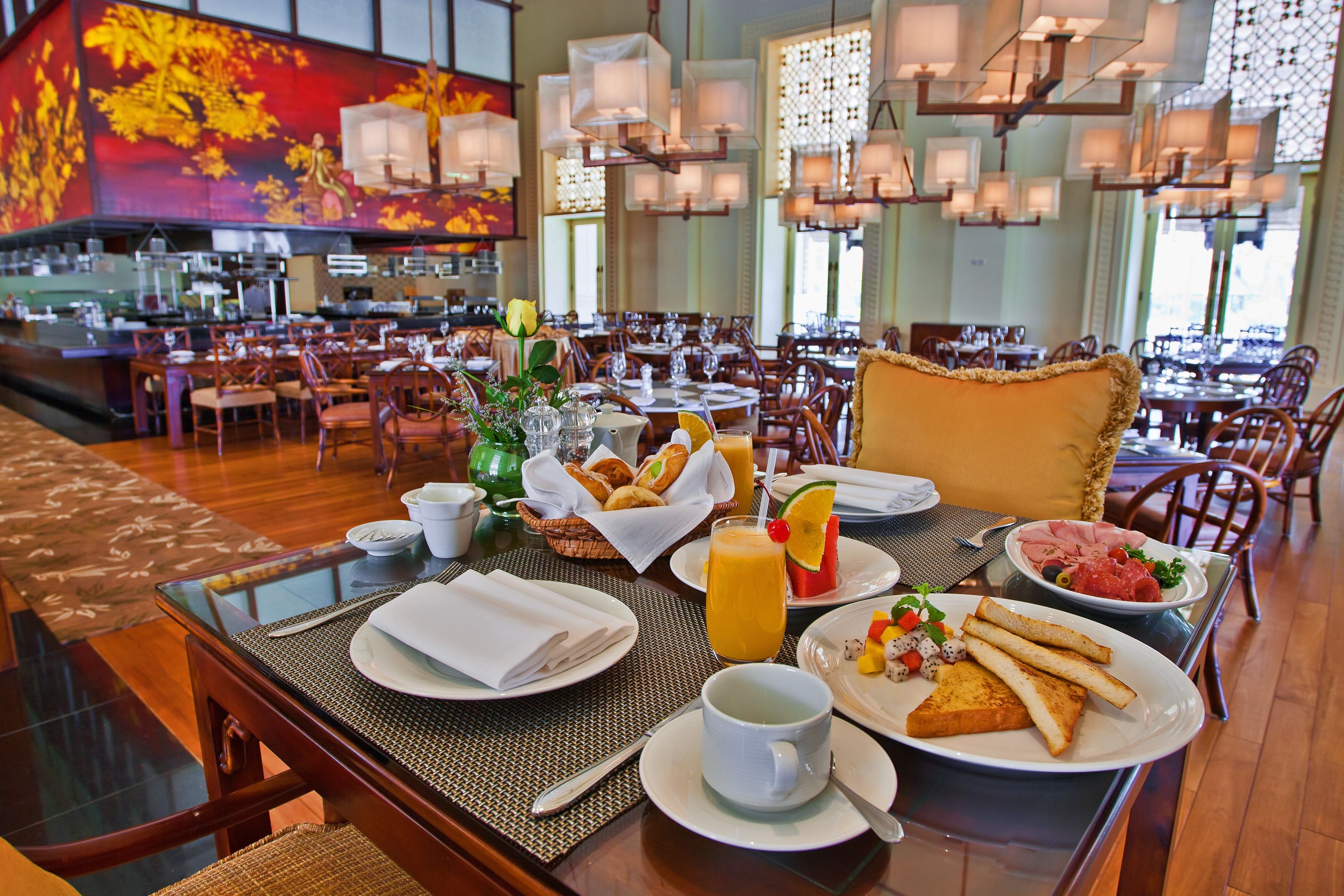 A breakfast setting with a table set for two, including plates of toast, fruit, and a cup of coffee.