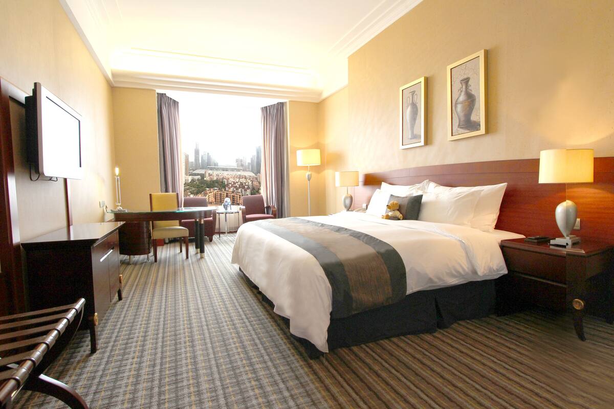 Une chambre d’hôtel avec un grand lit, un bureau, une chaise, une télévision et une vue sur le paysage urbain.