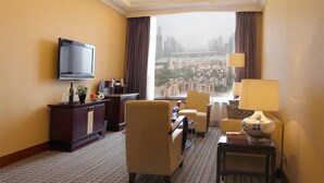 A hotel room with a television, a desk with a lamp, a chair, and a view of a cityscape. - Asta Hotel (Shenzhen)