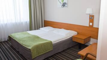A hotel room with a bed, a nightstand, a desk, and a chair.