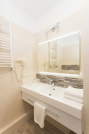 A bathroom with a white sink, mirror, towel rack, and a towel hanging on the rack.