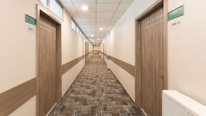 Un pasillo de hotel con pisos alfombrados, puertas de madera y letreros que indican los números de las habitaciones.