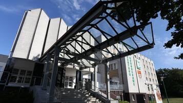 A modern building with a prominent entrance, a staircase, and a large banner.