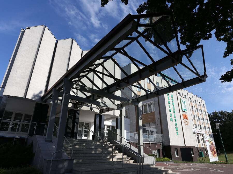 Un bâtiment moderne doté d’une entrée imposante, d’un escalier et d’une grande bannière.