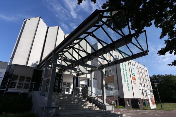 Un edificio moderno con una entrada destacada, una escalera y un cartel grande.