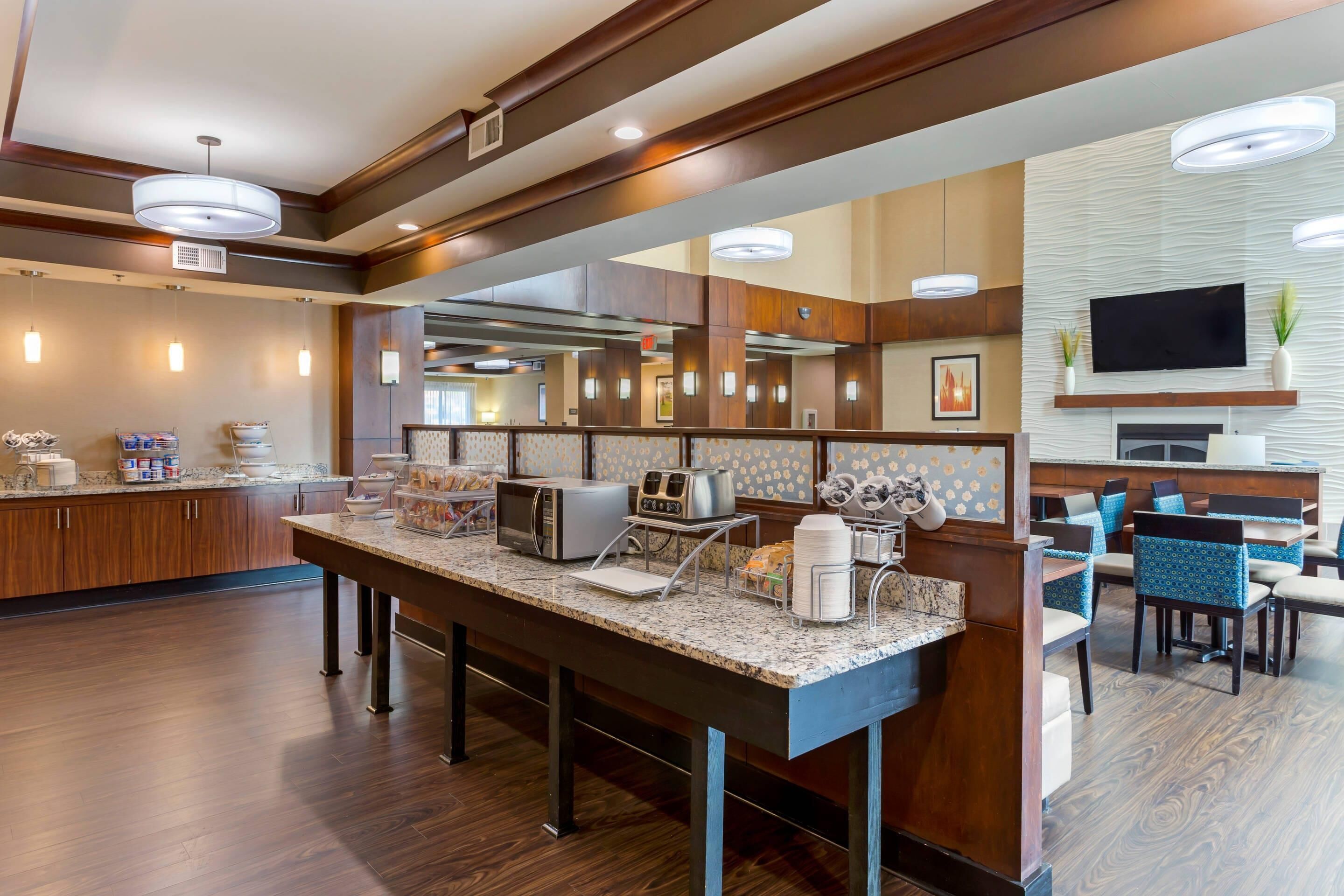 A modern kitchen area with a central island, built-in appliances, and a seating area with chairs and a table. - Comfort Suites Little Rock West (Little Rock)