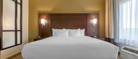 A hotel room with a large bed, two bedside lamps, a nightstand, and a window with curtains.