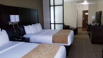 Habitación de hotel con dos camas, un escritorio, una cómoda y un ventanal grande.
