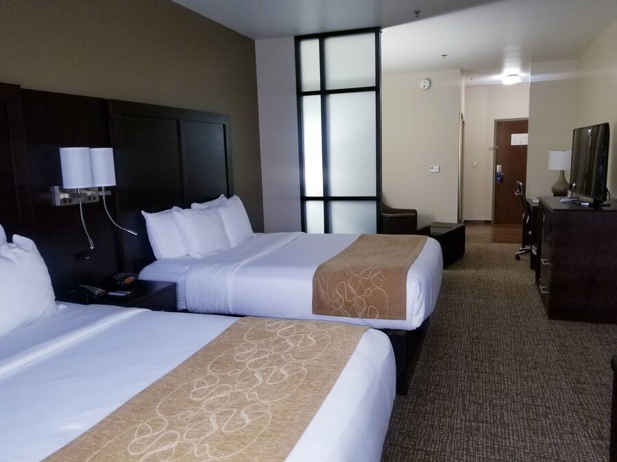 Habitación de hotel con dos camas, un escritorio, una cómoda y un ventanal grande.