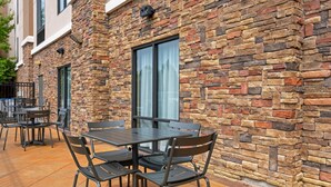 An outdoor patio area with stone walls, metal tables, and chairs. - Comfort Suites Little Rock West (Little Rock)