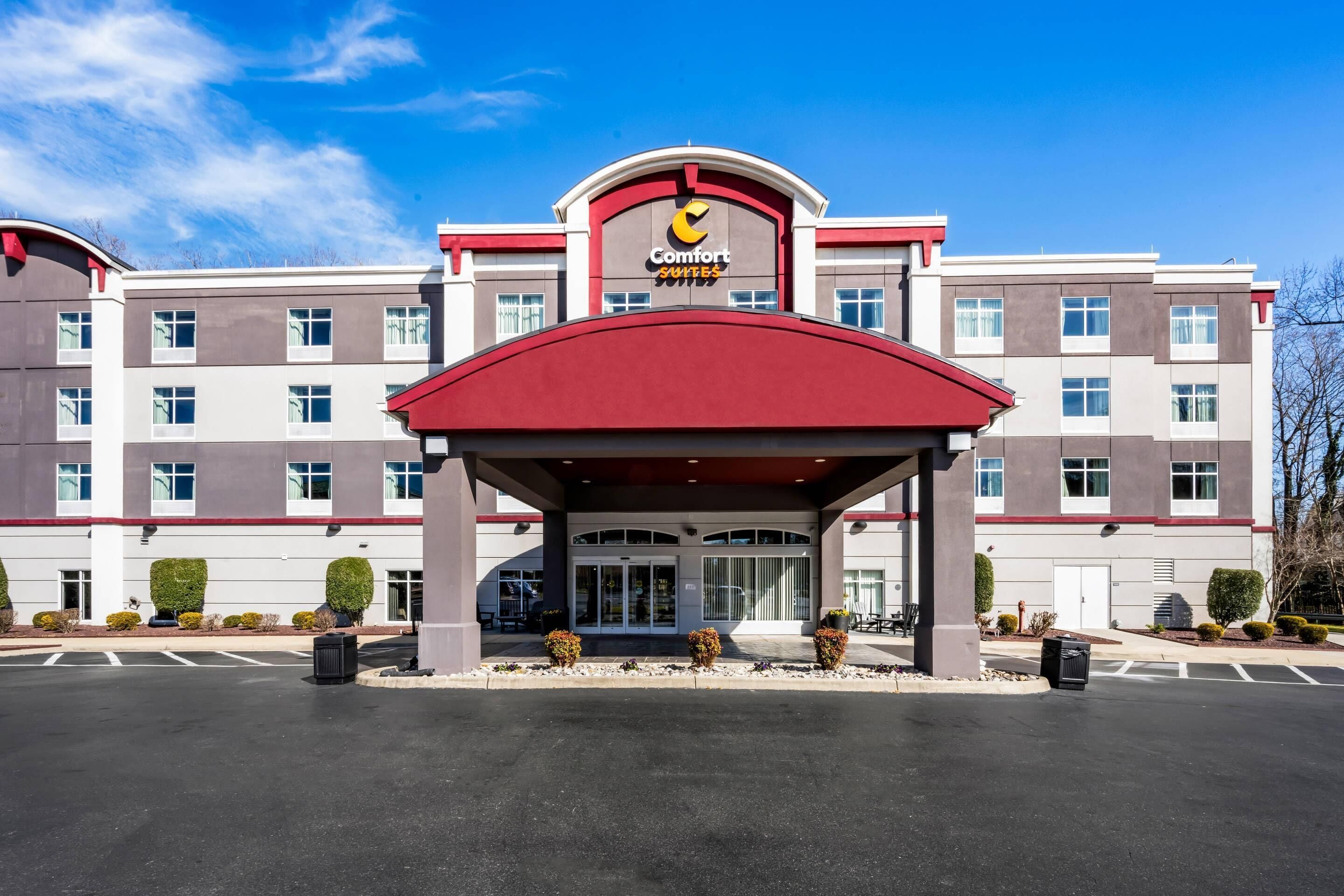 A hotel with a red entrance canopy, multiple floors, and a clear sky.