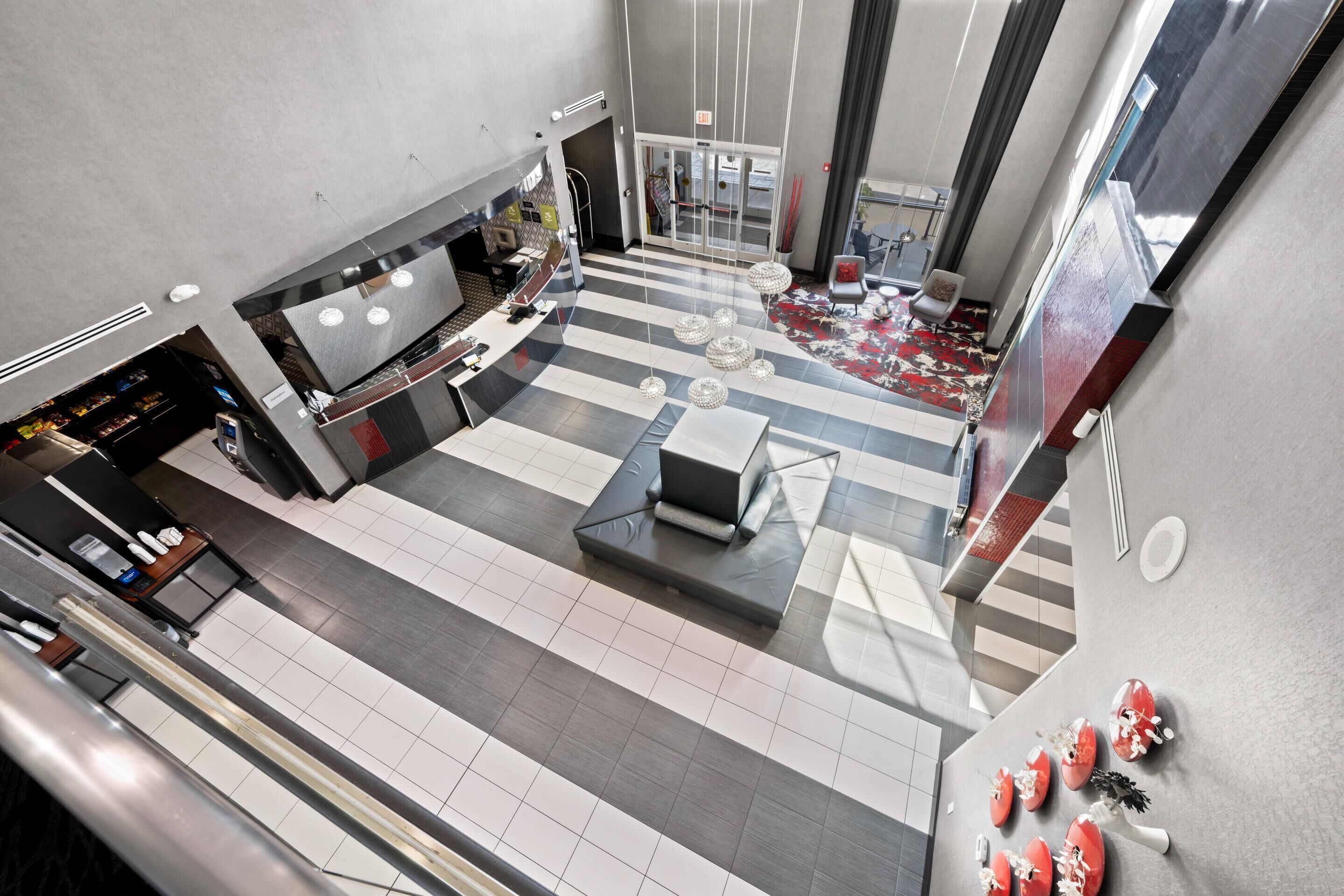 A spacious lobby with a check-in counter, seating area, and a staircase leading to upper floors.