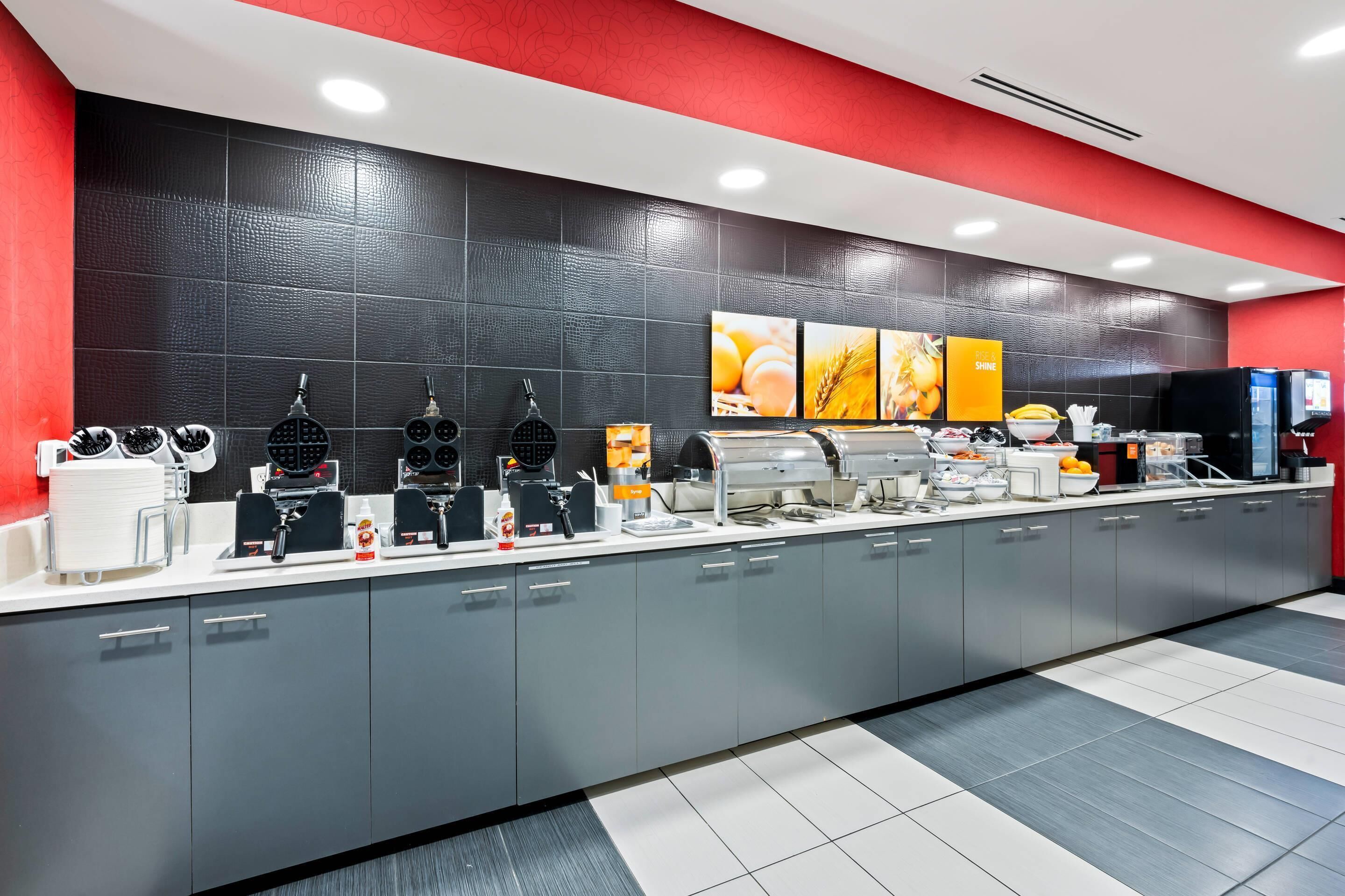 A modern kitchen with a long counter, multiple appliances, and a tiled backsplash.