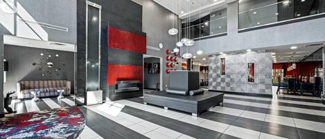 A spacious lobby with a checkered floor, a sofa, a fireplace, and a modern reception desk.
