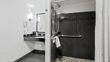 A modern bathroom with a shower, a towel rack, a sink with a mirror, and a telephone.