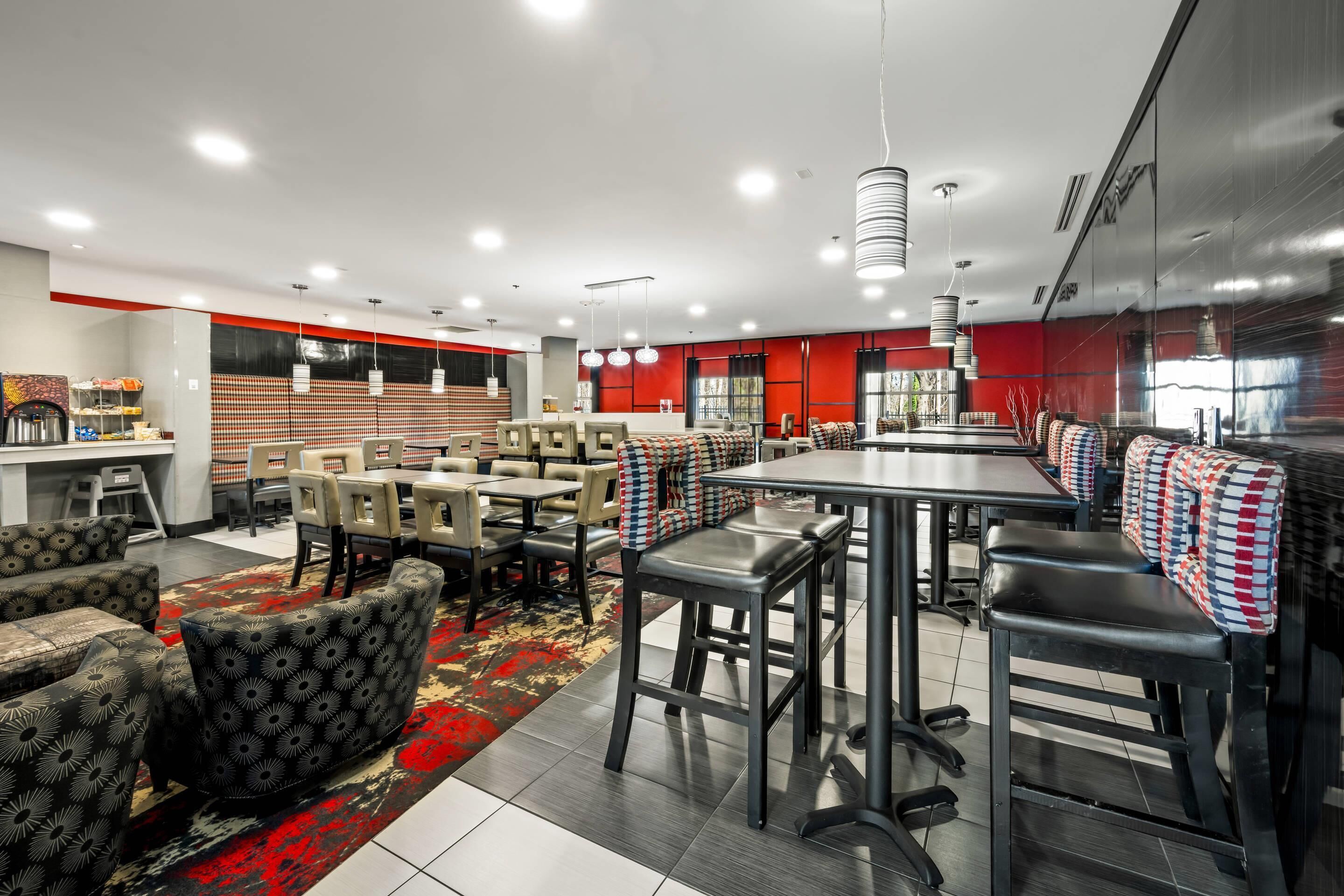 Un restaurante moderno con techos altos, iluminación colgante y una combinación de asientos tipo cabina y barra.