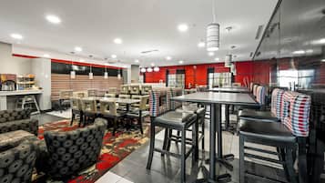 Un restaurante moderno con techos altos, iluminación colgante y una combinación de asientos tipo cabina y barra.