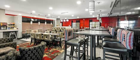 Un restaurante moderno con techos altos, iluminación colgante y una combinación de asientos tipo cabina y barra.